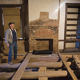 Ray Glendening observes the interior the house being restored. Note the trees that were used whole under the floor.