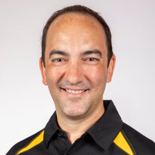 Portrait of Eric Aldrich in black and gold polo
