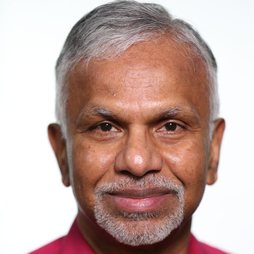 Portrait of Hari Krishnan wearing red button up shirt.