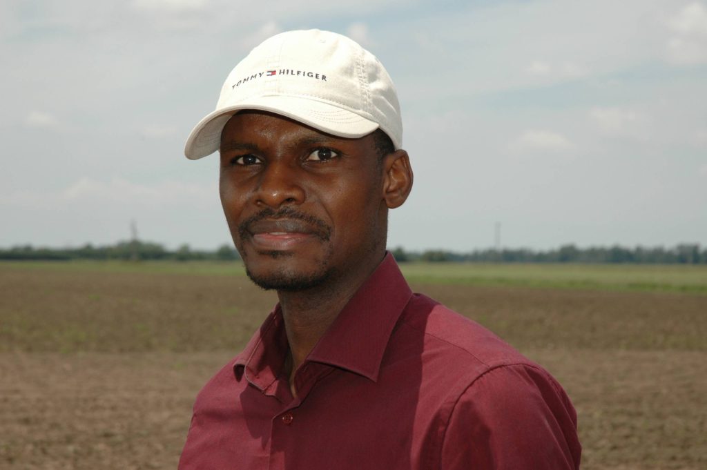 black man wearing a white cap and maroon polo shirt