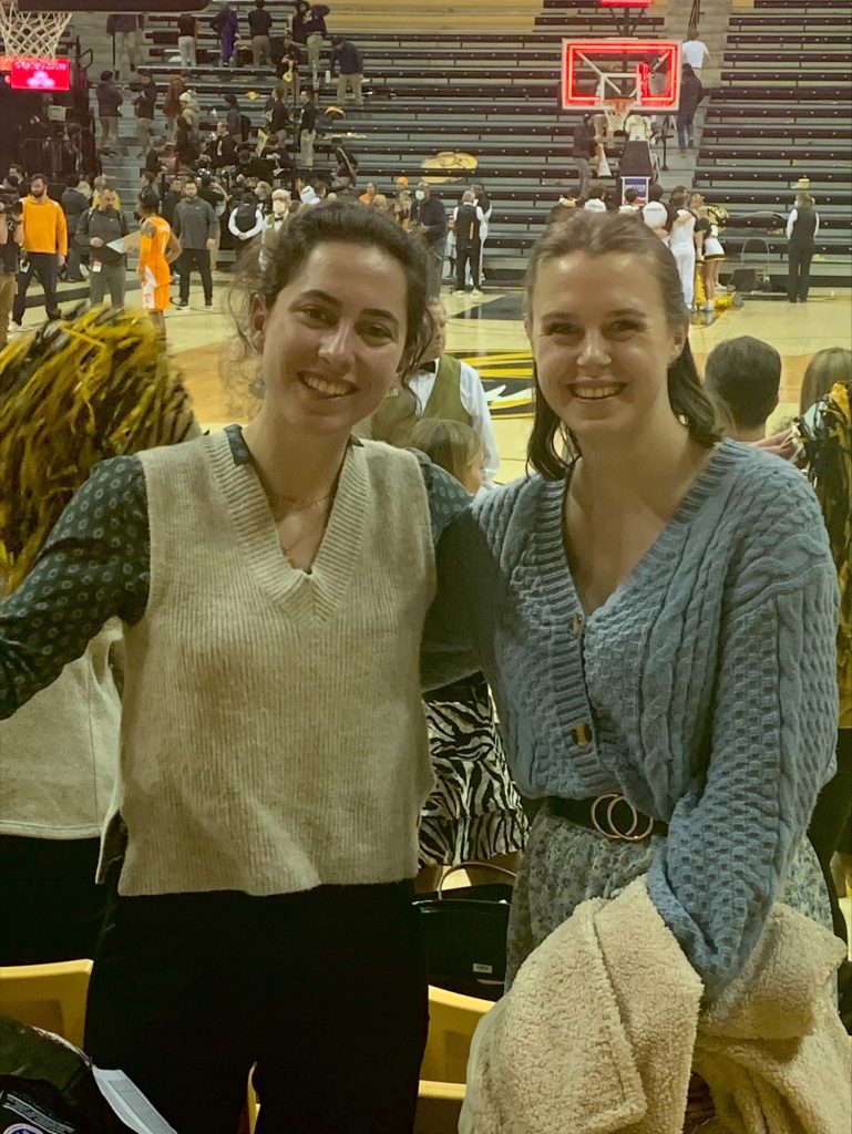 two women stand near the basketball court at a Mizzou game