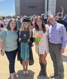A father, mother, and two daughters pose at one daughter's college graduation.