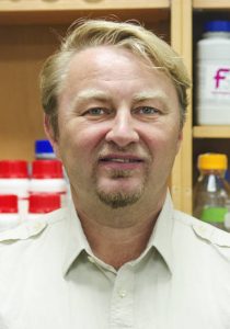 Photo of Peter Sutovsky, a white man with blonde hair, blue eyes wearing a white button up shirt