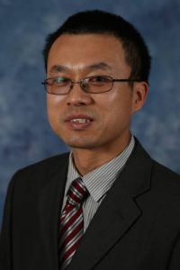 Photo of Jianfeng Zhou. Asian man with dark hair and glasses, wearing a dark suit with a red and silver striped tie.