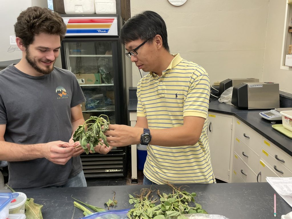 two men holding a plant in a lab