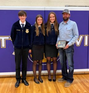 Shawn poses with three high school FFA students who are presenting him with an award