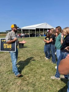 Shawn speak to students in a field.