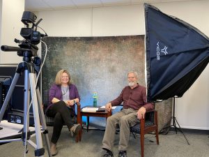 Ray sits next to Julie Harker in a makeshift video studio, offering a behind the scenes look into their ag leasing webinar series. 