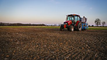 A red tractor sits in a harvested corn field