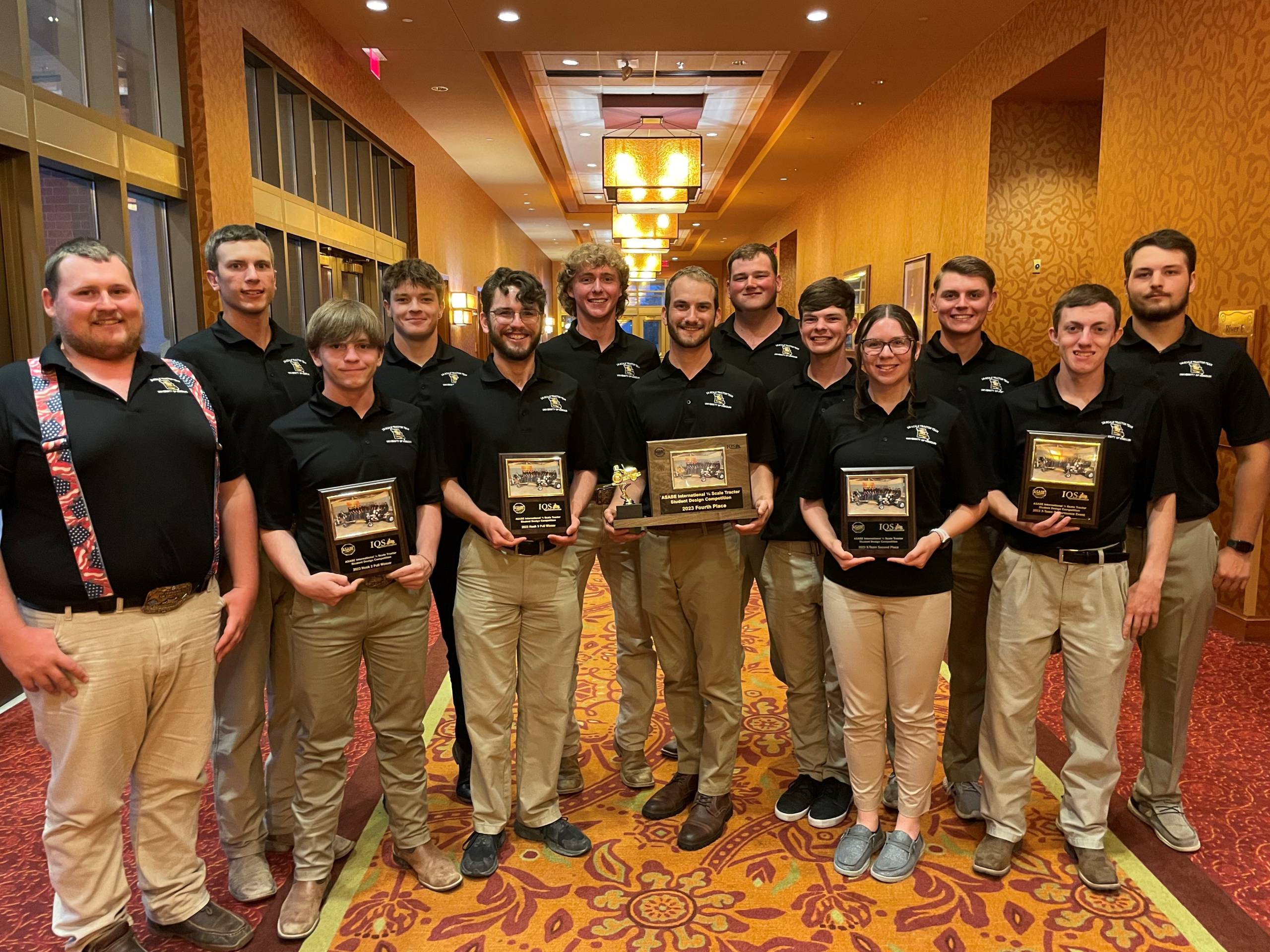 Student team members hold plaques at awards banquet for quarter-scale tractor competition.