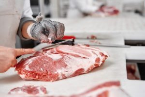 A hand is shown slicing some raw beef.