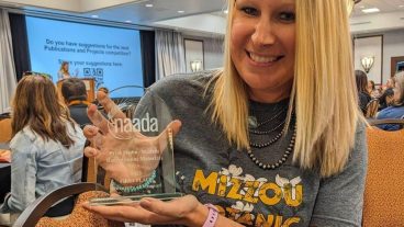 Smiling blond woman holds clear glass award