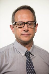 Tony Lupo wearing dark glasses, light grey shirt and striped tie.