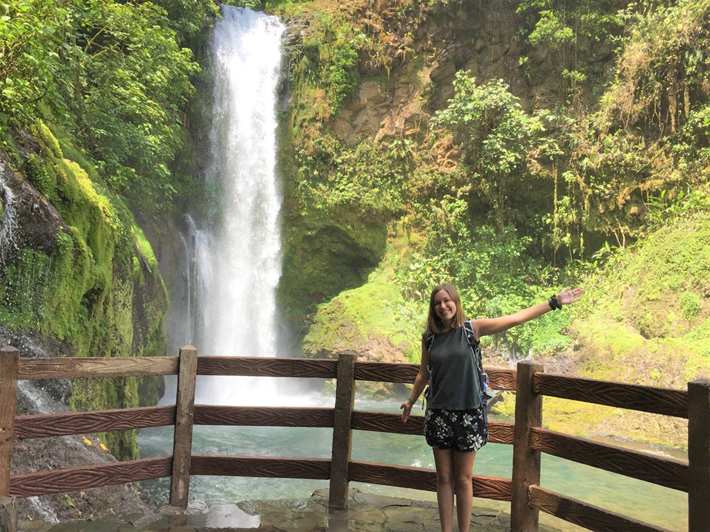 student in front of waterfall