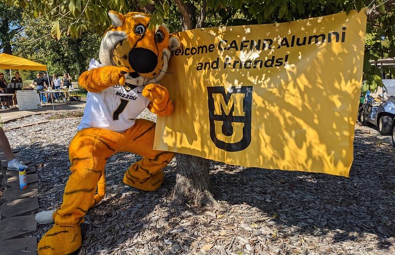 Truman, Mizzou's mascot, stands in front of a sign reading "Welcome CAFNR Alumni and Friends"