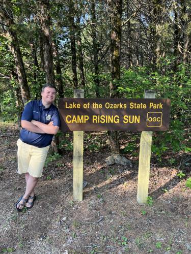 Grant Norfleet next to the Camp Rising Sun sign. 