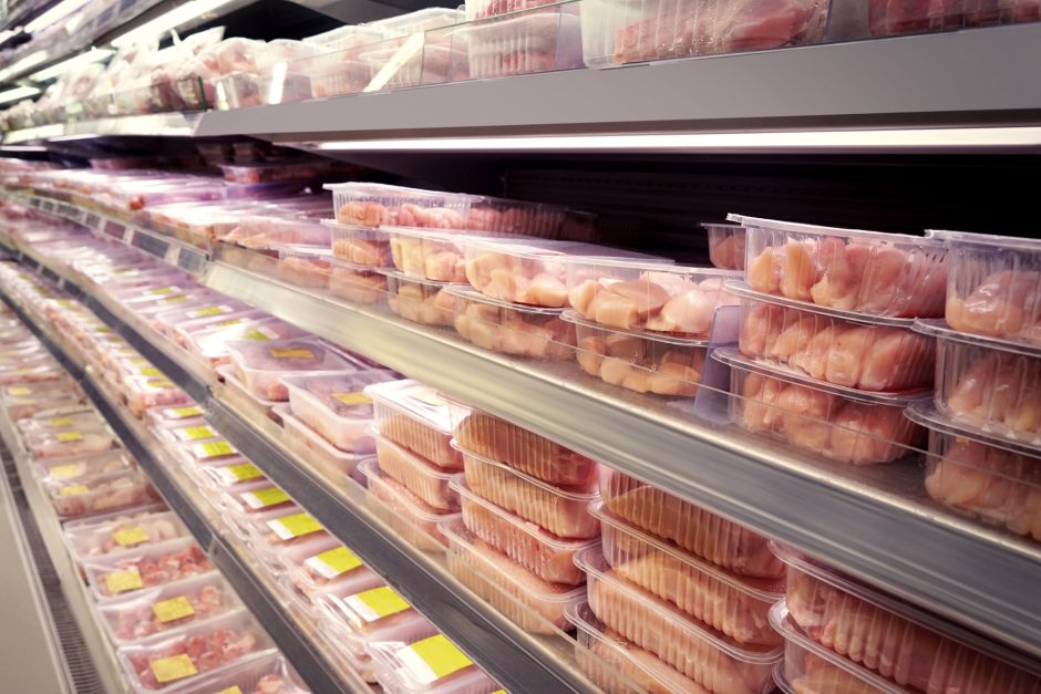 Packages of raw chicken line a cooler case in a grocery store.