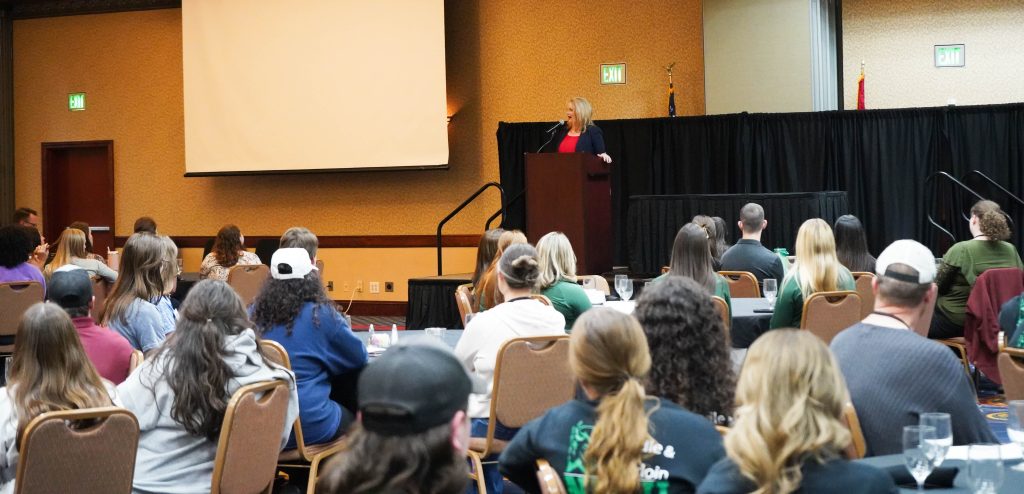 A woman speaks to a room full of students. 