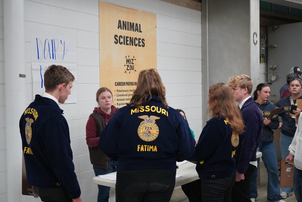 FFA students stand at a table speaking to a Mizzou student. 