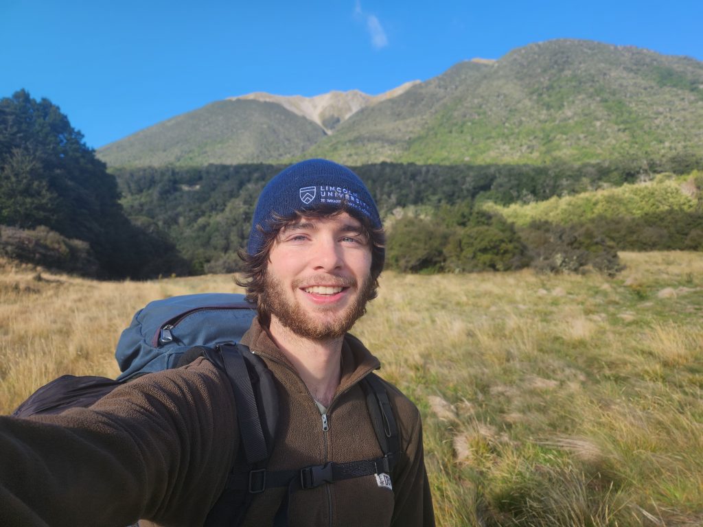 A student poses for a selfie in front of mountains.