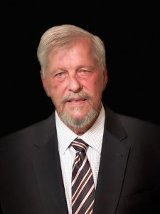 Portrait of Bob in dark suit and striped tie.