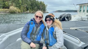 Two women pose on a small boat.