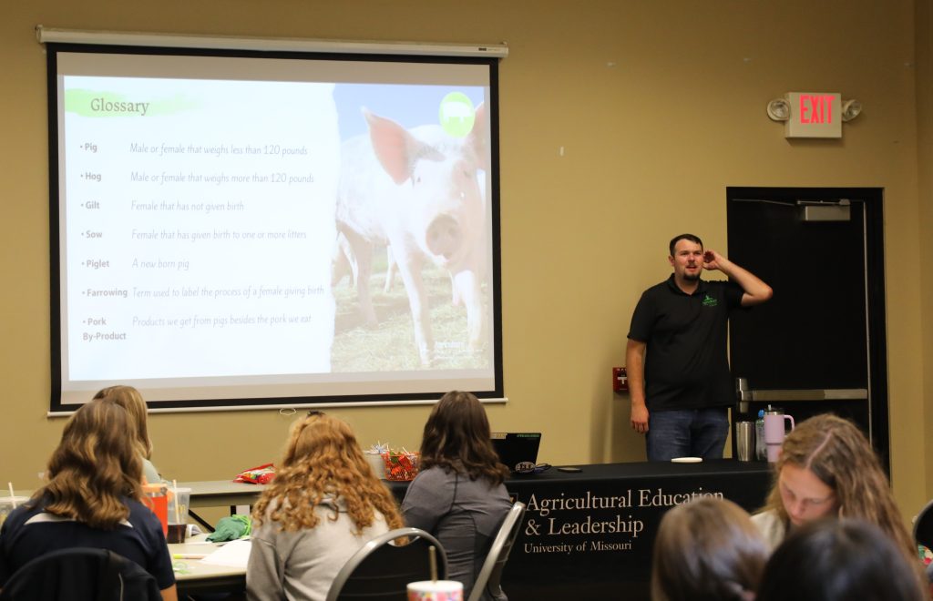 A student presents a PowerPoint presentation to a room of other students.