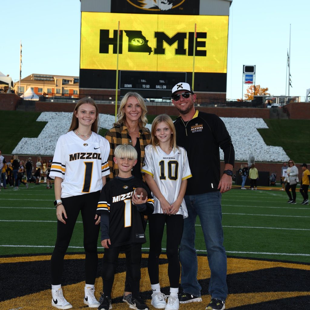 A family poses for a photo on Faurot Field. 