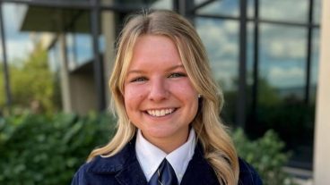 A student in an FFA jacket poses for a portrait.