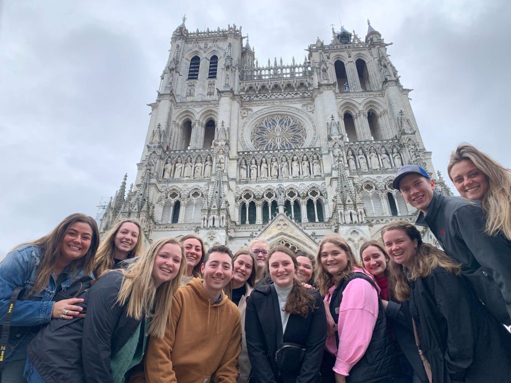 Students pose in front of a cathedral in France. 