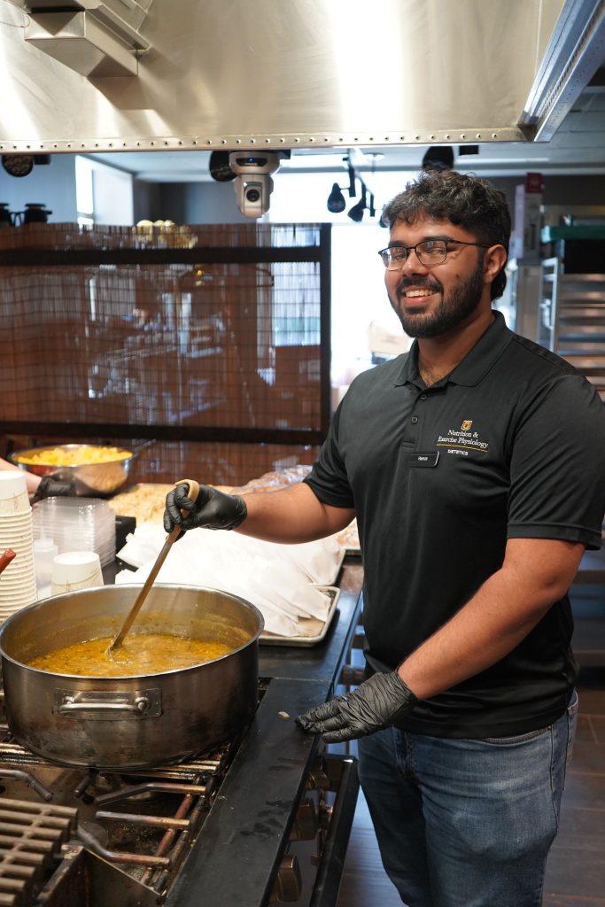 A student stirs a pot of soup. 