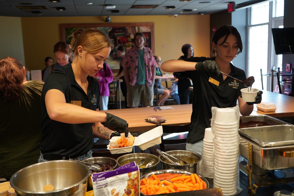 Two students serve food. 