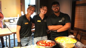 Three students pose in a kitchen.