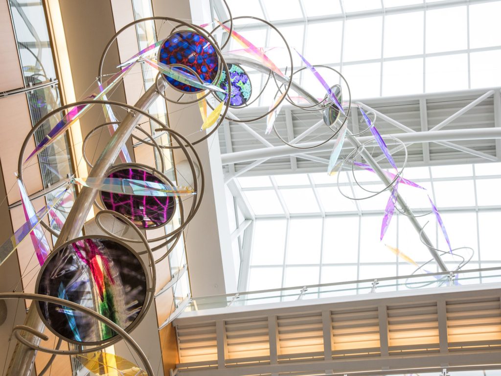 A colorful, winding sculpture against a glass ceiling.