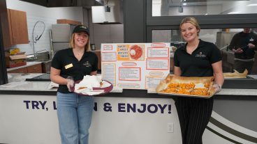 Two students pose with trays of food.