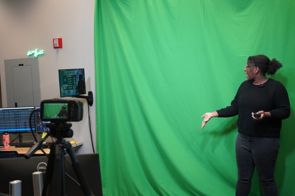 A student does a weather forecast in front of a green screen.