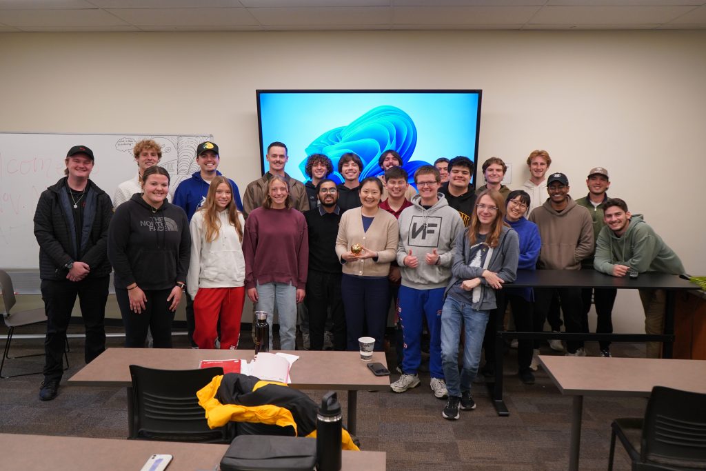 A group of students poses for a photo with their professor. 