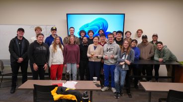 A group of students poses for a photo with their professor.