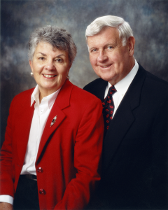 Portrait of Al and Mary Agnes McQuinn. Mary Agnes is in a red suit coat, and Al in navy blue.