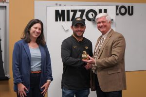 Three people pose for an award presentation.