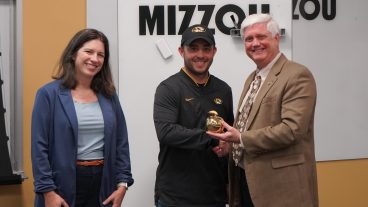 Three people pose for an award presentation.