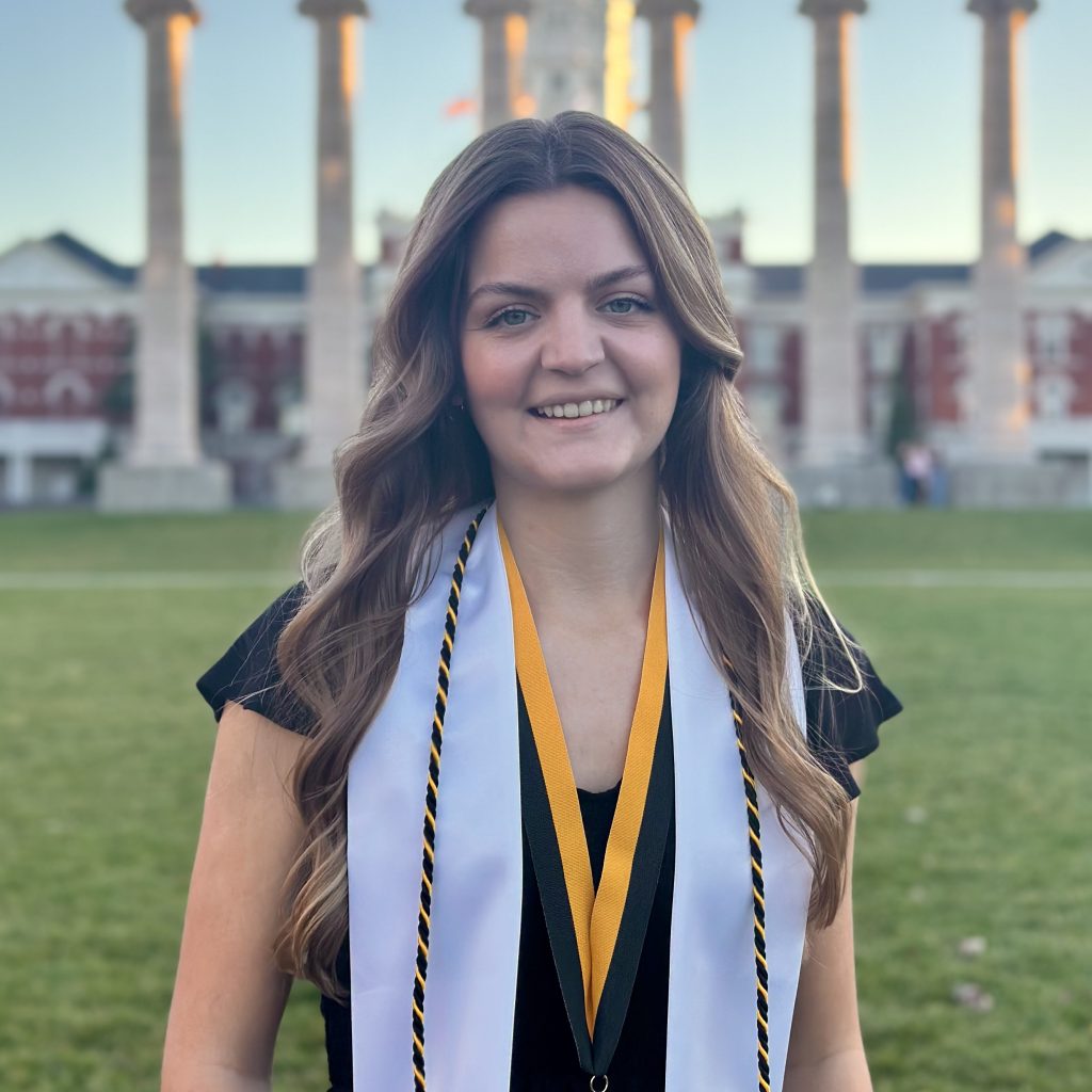 A student poses for a portrait in front of the Columns. 