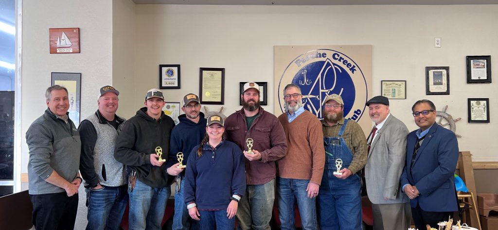 Nine people line up and post with an award in an office.