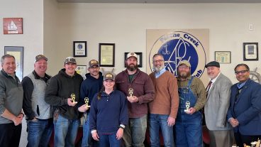 Nine people line up and post with an award in an office.