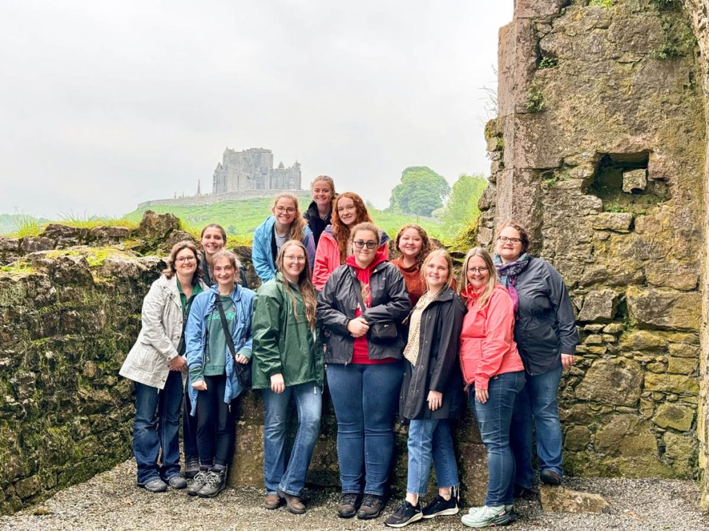 Group smiling in front of castle ruins.