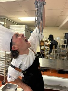 Ben Laizerovich holding up spaghetti noodles.