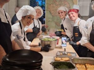 Group of culinary students smiling in kitchen.