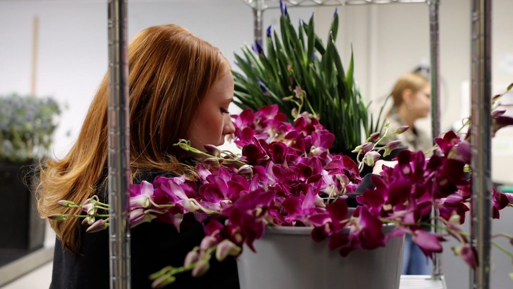 Female student arranging flowers on a shelf.