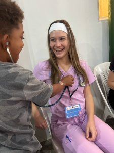 Eva Ruterschmidt smiles as she lets a child use a stethoscope on her.