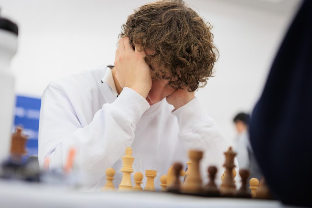 Mahel Boyer holds his head in his hands in front of chess board.